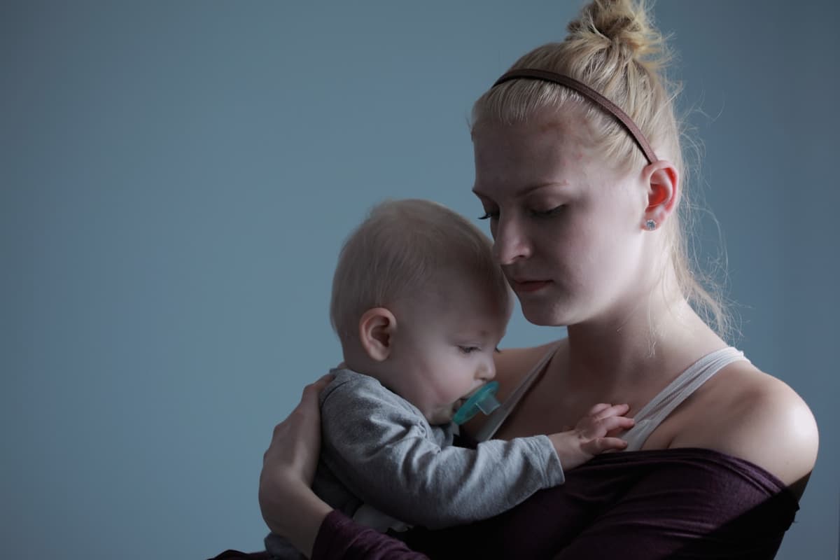 Ein Erwachsener hält ein Baby im warmen Abendlicht an der Schulter.