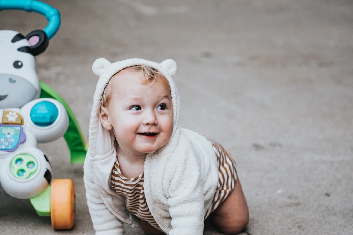 A baby up on hands and knees on the floor, mid-crawl.
