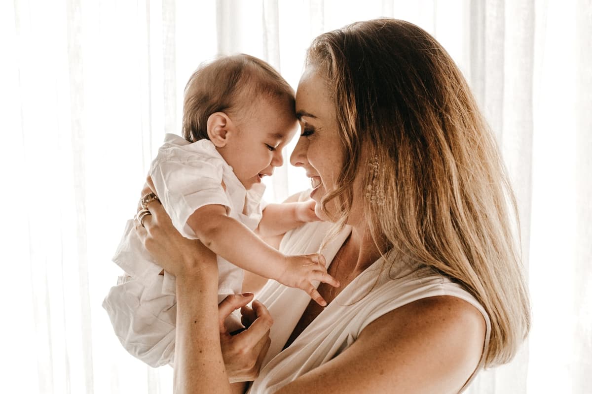 A parent holding a baby up at face height, the two of them forehead to forehead.